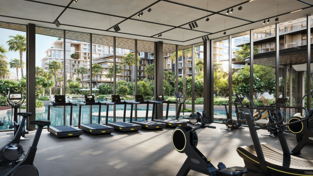 Salle de sport haut de gamme avec équipements modernes et grandes baies vitrées donnant sur la piscine
